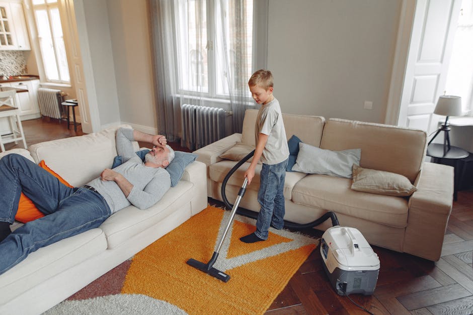 A person is kneeling on a patterned carpet in a residential setting, loading a white cloth into a yellow and black vacuum cleaner with a flexible hose, positioned on the carpet's surface. The scene is